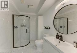 Curved glass shower enclosure with matte black framing, white tile walls and flooring, white vanity with integrated sink, matte black faucet, and a large round mirror - 