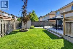 Expansive lawn area, raised wood deck, privacy fencing, and a covered patio structure - 