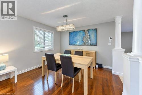 Wood-finish flooring with a rectangular chandelier, a window featuring blinds, and a built-in architectural column - 88 Decaro Crescent, Cambridge, ON 