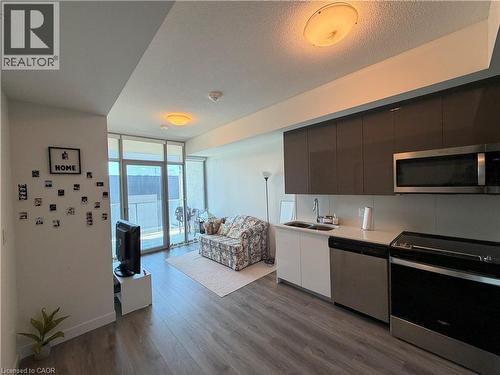 Wood-finish flooring throughout, full wall of floor-to-ceiling windows, modern kitchen cabinetry, stainless steel appliances, and a private balcony - 60 Frederick Street Unit# 1213, Kitchener, ON 