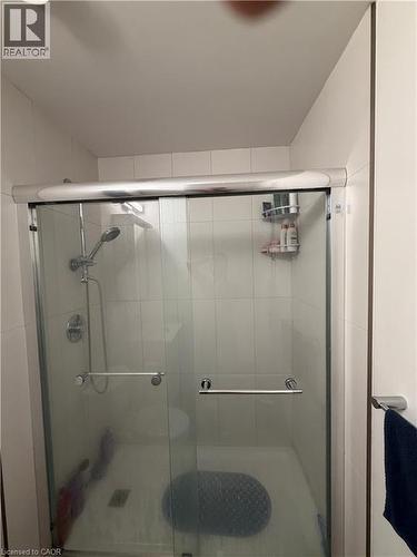 Glass-enclosed shower with white tiled walls, a built-in shower niche, and a chrome shower system - 60 Frederick Street Unit# 1213, Kitchener, ON 