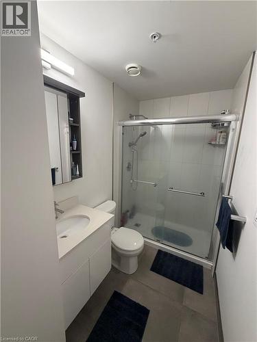 Bathroom featuring a shower enclosure with glass sliding doors, a white vanity with an integrated sink, and a mirrored medicine cabinet - 60 Frederick Street Unit# 1213, Kitchener, ON 