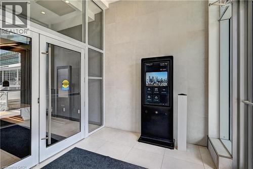 Glass entry doors with brushed metal handles, floor-to-ceiling glass paneling, a large digital display, and light-toned tile flooring - 60 Frederick Street Unit# 1213, Kitchener, ON 