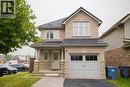 Brick exterior with stone accents, covered front porch, integrated garage, and a dark tile roof - 18 Heritage Drive, Guelph, ON 