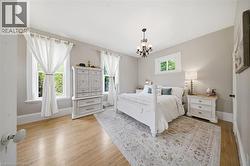 Well-lit room featuring wood-finish flooring, light gray walls, white trim, and a decorative chandelier - 