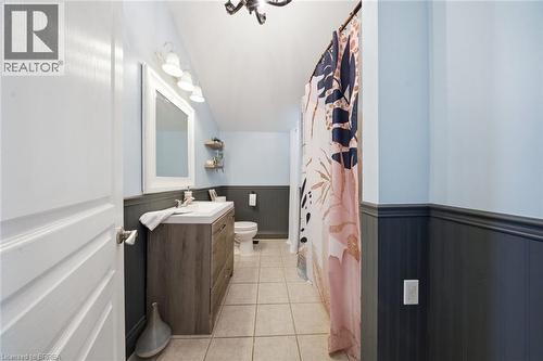 Bathroom featuring a wood-finish vanity with an integrated sink, a large wall mirror, and a three-light vanity fixture - 62 East Avenue, Brantford, ON 
