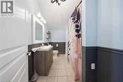 Bathroom featuring a wood-finish vanity with an integrated sink, a large wall mirror, and a three-light vanity fixture - 