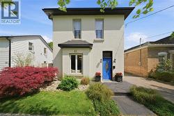 Brick exterior with a vibrant blue entry door, two exterior sconces, and a partial black roofline - 