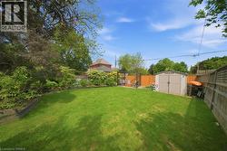 Expansive private backyard featuring a large lawn area, mature trees, and a storage shed - 