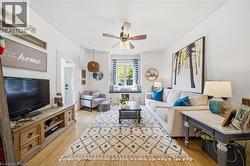 Living area featuring wood-finish flooring, white walls, and decorative crown molding - 