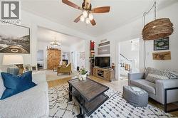 Bright living area featuring light wood-finish flooring, a ceiling fan, and decorative crown molding - 