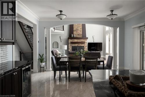 Arched entryway with column detailing, stone-accented fireplace, wood-finish mantel, and tiled flooring - 1505 Milburough Line, Carlisle, ON 
