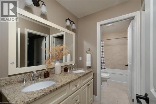 Dual vanity with integrated sinks, granite-finish countertop, and decorative wall-mounted light fixtures - 1505 Milburough Line, Carlisle, ON 