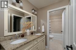 Dual vanity with integrated sinks, granite-finish countertop, and decorative wall-mounted light fixtures - 