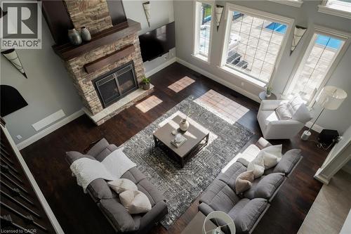 Stone-clad fireplace with wood mantle, dark wood-finish flooring, tall windows, and recessed lighting - 1505 Milburough Line, Carlisle, ON 