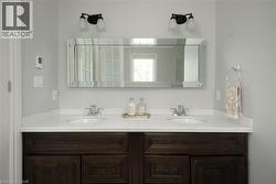 Dual vanities with undermount sinks, white solid-surface countertop, dark wood-finish cabinetry, and a beveled mirror - 