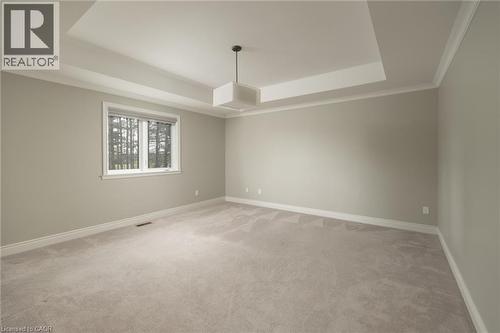 Recessed tray ceiling, neutral wall color, crown molding, window with outdoor scenery, and light-colored carpeting - 1505 Milburough Line, Carlisle, ON 