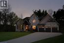 Stone exterior with a three-car garage, arched entry, and a paved driveway - 1505 Milburough Line, Carlisle, ON 