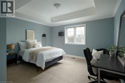 Tray ceiling with crown molding, carpeted flooring, and a large window with white trim - 