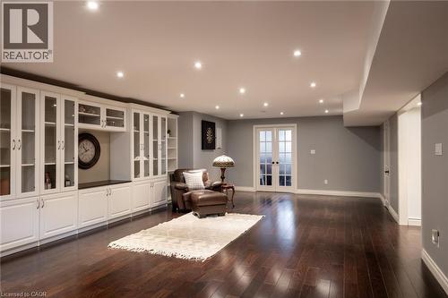 Dark wood-finish flooring, recessed lighting, expansive white built-in cabinetry with glass fronts, a built-in counter, and double French doors - 1505 Milburough Line, Carlisle, ON 