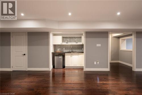 Dark wood-finish flooring, recessed lighting, and a wet bar featuring white cabinetry, a dark countertop, and a tiled backsplash - 1505 Milburough Line, Carlisle, ON 