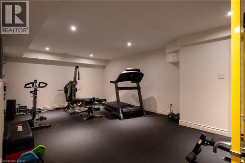 Recessed ceiling lighting illuminates a spacious room featuring a dark rubber-finish floor and white painted walls - 1505 Milburough Line, Carlisle, ON 