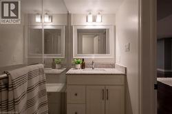 White vanity with shaker-style cabinetry, a speckled countertop, and an undermount sink - 
