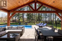 Covered outdoor living space featuring a wood-beam ceiling, exposed structural timbers, and recessed lighting - 