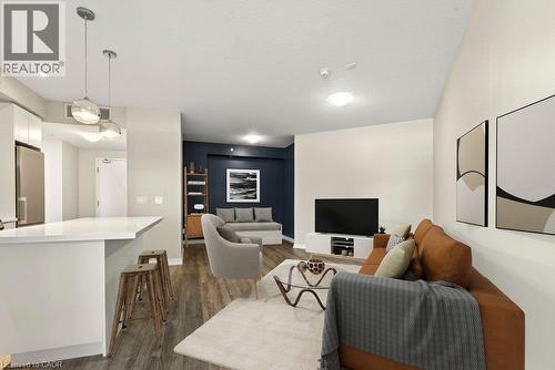 Open-concept living space featuring wood-finish flooring, a kitchen island with a white countertop, two pendant lights, and recessed ceiling lighting - 457 Plains Road Unit# 225, Burlington, ON 