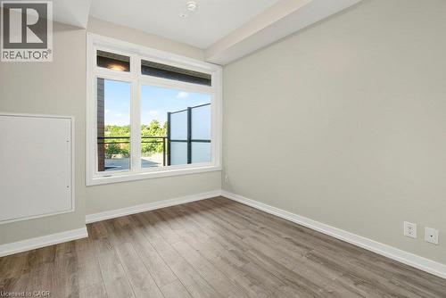 Room featuring wood-finish flooring, a large window, light-colored walls, white baseboards, and a recessed ceiling light - 457 Plains Road Unit# 225, Burlington, ON 