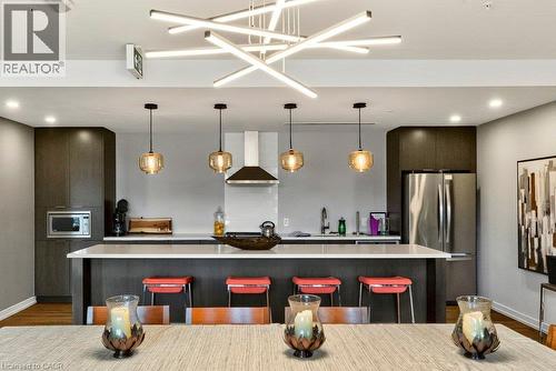 Kitchen featuring dark wood-finish cabinetry, stainless steel appliances, and a central island with white countertops - 457 Plains Road Unit# 225, Burlington, ON 