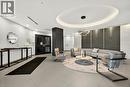 Modern lobby featuring light-toned tile flooring, a circular ceiling detail with recessed lighting, a contemporary chandelier, textured wall panels, and double entry doors - 457 Plains Road Unit# 225, Burlington, ON 