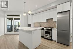 Modern kitchen featuring white cabinetry, a central island with a solid surface countertop, and stainless steel appliances - 