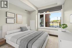 Spacious room featuring a large window, a built-in window bench with storage, textured light-colored walls, wood-finish flooring, and a white ceiling - 