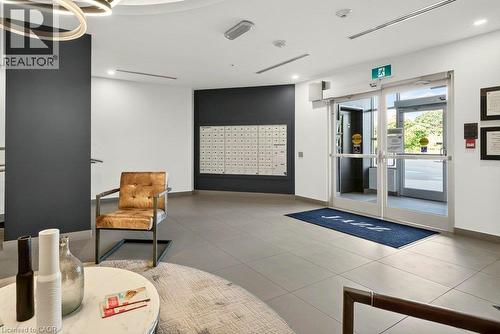 Lobby entrance featuring large format tile flooring, a wall of individual mailboxes, and double glass-paneled doors with aluminum frames - 457 Plains Road Unit# 225, Burlington, ON 
