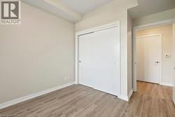 Room featuring wood-finish flooring, a sliding closet door with a circular handle, and light-toned walls - 