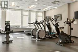 Fitness center with multiple cardio machines, television screens, recessed lighting, and large windows with roller shades - 