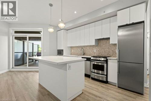 Modern kitchen featuring white cabinetry, a central island with a solid surface countertop, and stainless steel appliances - 457 Plains Road Unit# 225, Burlington, ON 