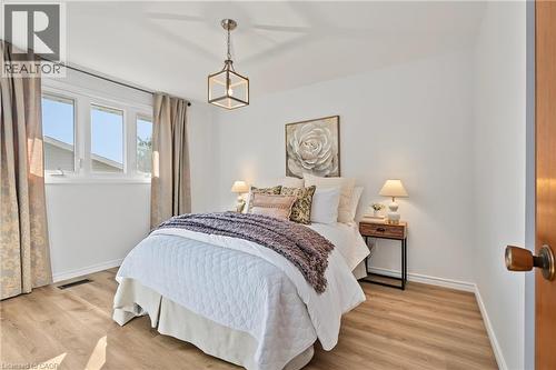PRIMARY BEDROOM with NEW vinyl flooring, large closet, vinyl windows & elegant new light fixture. - 589 Mohawk Road W, Hamilton, ON 