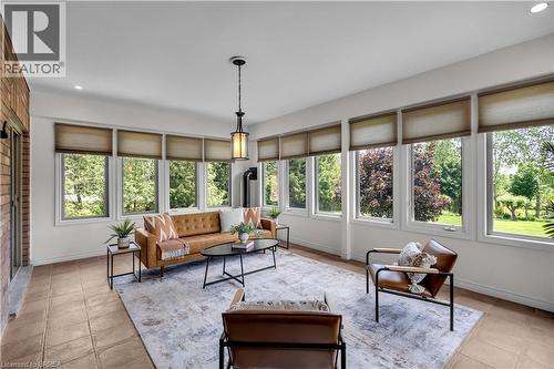 Sunroom with extensive window placement, tile flooring, and a detailed pendant light fixture - 302 German School Road, Paris, ON 