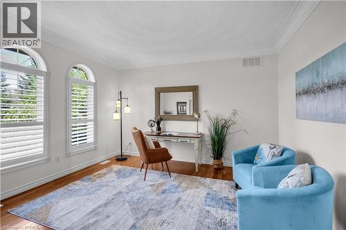 Bright room featuring two arched windows with louvered shutters, crown molding, wood-finish flooring, and white baseboards - 302 German School Road, Paris, ON 