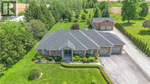 Expansive property featuring a brick exterior, multiple attached garage bays, a paved driveway, and an additional detached garage structure - 302 German School Road, Paris, ON 