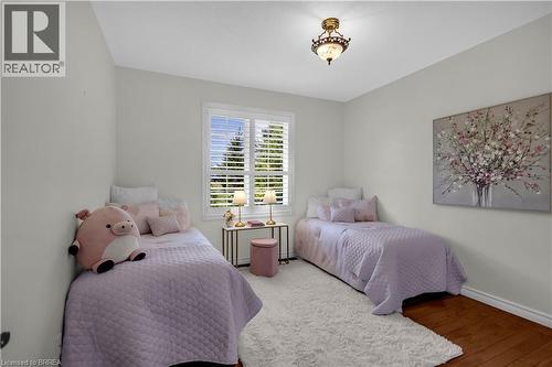 Bright room with a window featuring white plantation shutters, a decorative ceiling light fixture, and wood-finish flooring - 302 German School Road, Paris, ON 
