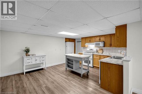 Kitchen featuring wood-finish cabinetry, white tile backsplash, and stone-look countertops - 302 German School Road, Paris, ON 