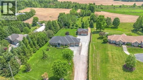 Expansive property featuring a brick residence with a gabled roofline, a lengthy paved driveway, mature trees, and an additional brick outbuilding - 302 German School Road, Paris, ON 
