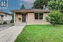 Brick exterior with a dark entry door, single-pane windows, paved walkway, and a manicured lawn - 143 Sunrise Place, Kitchener, ON 