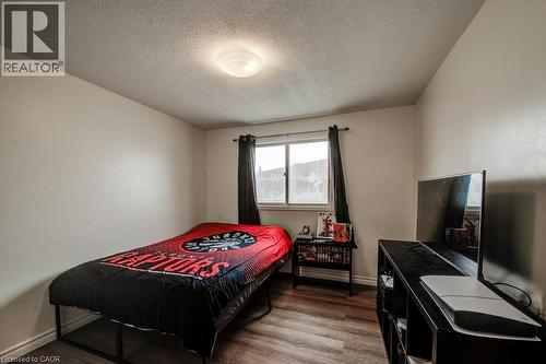 Bright secondary bedroom featuring wood-finish flooring, recessed ceiling lighting, and a large window with blackout curtains - 143 Sunrise Place, Kitchener, ON 