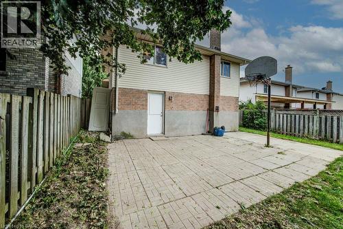 Paved patio area with direct exterior access, brick and siding exterior, and a privacy fence - 143 Sunrise Place, Kitchener, ON 