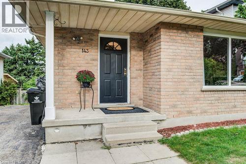 Brick exterior with a covered entryway, front door with an arched window, and a large front window - 143 Sunrise Place, Kitchener, ON 