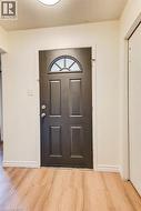 Entry door with an arched transom window, paneled design, and wood-finish flooring - 